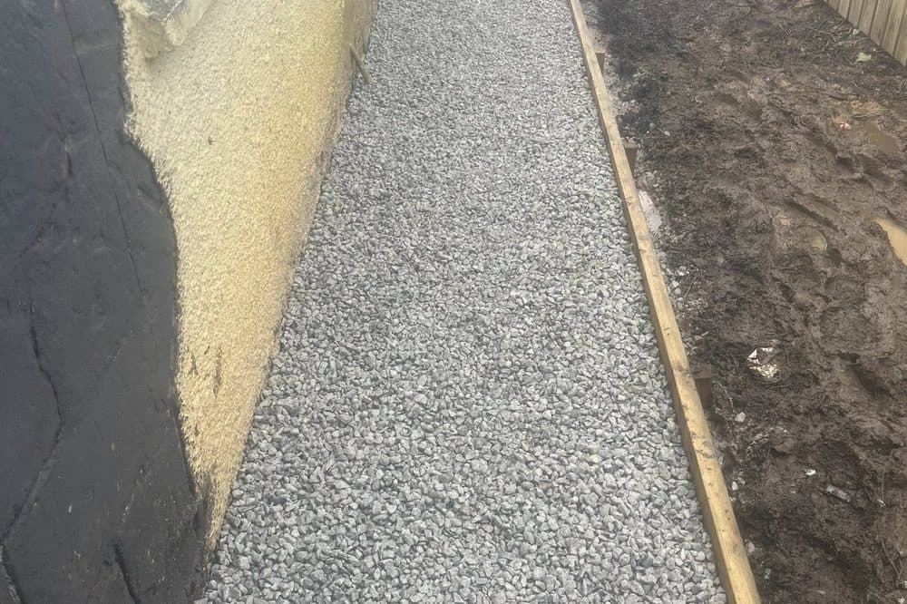 After: completed gravel path with timber edging laid alongside the house